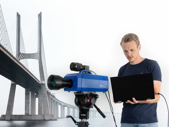 Optomet Nova-Xtra Laser Doppler Vibrometer performing a measurement on a bridge structure; a person monitors the data on a laptop.